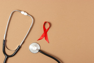 Red ribbon on a colored background. International cancer symbol.