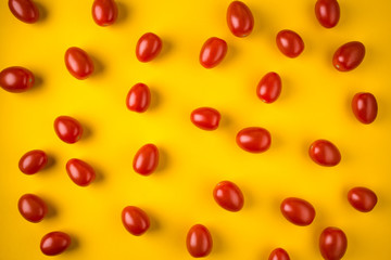 Flat lay with red cherry tomatoes on yellow background