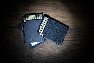 SD data cards on desktop, under round light as if discovered under flashlight investigation.