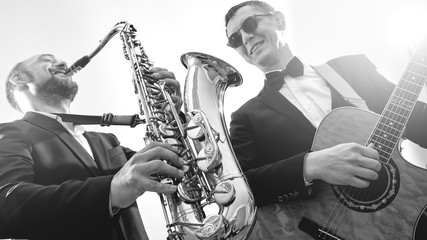 Group of two musicians, male jazz band, guitarist and saxophonist in classical costumes improvise...