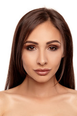 Fototapeta premium Close up portrait of a brunette nude model girl with professional evening make-up and plump lips, posing isolated on white background.