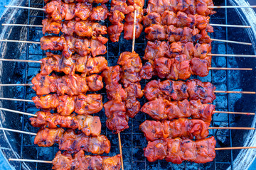 Thai street vendor sells grilled chicken meat at street food market in island Koh Phangan, Thailand. Closeup