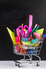 Shopping cart stocked with school supplies and a blackboard