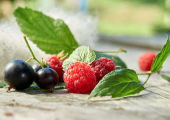 Fresh berries on wooden background. Raspberries and black currants.