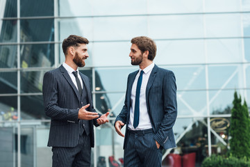 Two smiling businessman colleagues in a blue suit talking and walking business people discussing strategy in a modern city