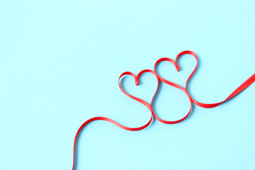 hearts from ribbons on a colored background top view.