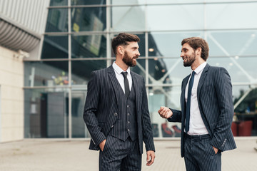 Two smiling businessman colleagues in a blue suit talking and walking business people discussing...