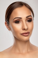 Fototapeta premium Close up portrait of a brunette nude model girl with professional evening make-up and plump lips, posing on gray background.