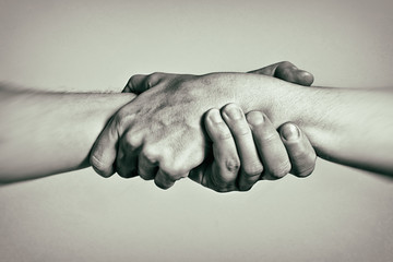 Concept of salvation. Image of the hands of two people at the time of rescue (help). Black and white.