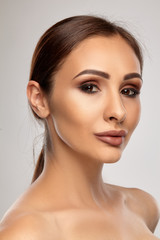 Fototapeta premium Close up portrait of a brunette nude model girl with professional evening make-up and plump lips, posing on gray background.