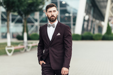 Young and successful. Handsome young man in full suit adjusting his jacket while standing outdoors