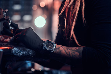 Closeup photo shoot of tattoo making, artist is working with tattoo machine on customer's hand.