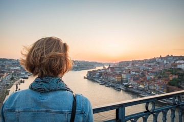 Fototapeta na wymiar redhead woman observing the sunset in porto, portugal on the bridge over the river
