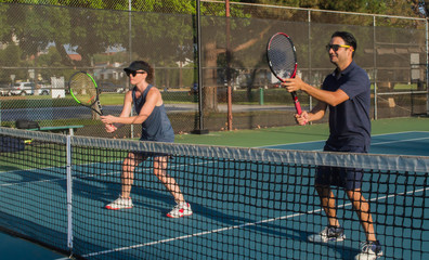 Men and women taking an outdoor tennis lesson