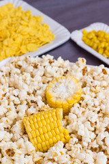 a set of products made from corn: popcorn, boiled grains, and cereals. White plates