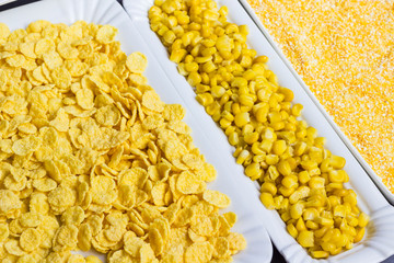 A set of products made from corn: boiled grains, cereals, and corn grits. White plates
