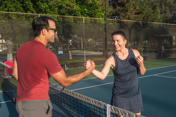 Men and women taking an outdoor tennis lesson