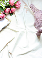 Morning  lifestyle flat lay with peony flowers and lace lingerie. Top view on the bed sheets