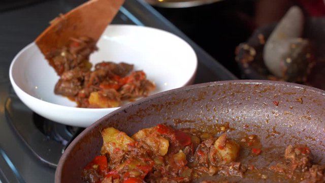 Frying pan with onion, lemongrass, red pepper and beef meat, close up. Indonesia. Sambal Goreng Ati Kentang, Indonesian cuisine, spicy beef meet and potatoes garnish with lemongrass leaf and red chili