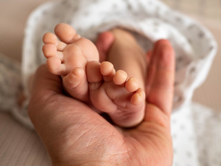 Newborn baby feet in mans hand