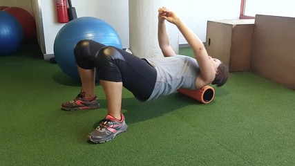 A girl on a myofascial roller, performs the massage itself, for rehabilitation after a back injury.