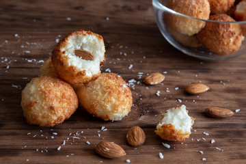 Coconut cookies with almonds lie on a wooden table.
