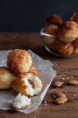 Coconut cookies with almonds lie on a wooden table.