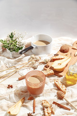Coffee with milk, cookies, cinnamon and fruits on the tablecloth.