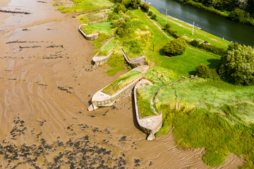 Aerial drone view of silt filled abandoned ships on the banks on a muddy river