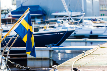 Sailing boats on the pier, port of Riga, Latvia. Flag of Sweden close-up