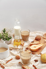 Coffee with milk, cookies, cinnamon and fruits on the tablecloth.
