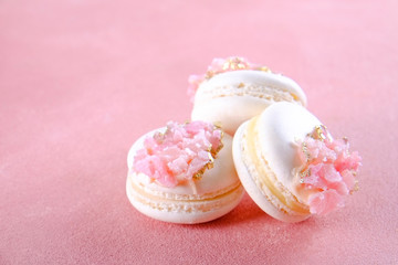 Minimalistic composition with bunch of white french macaron sweets with pink crystal shaped marmalade decoration over grunged concrete texture background. Top view, close up, flat lay, copy space.