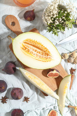 Cut appetizing ripe melon and drinks in stained-glass glasses on a table with a blue tablecloth.