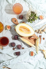Cut appetizing ripe melon and drinks in stained-glass glasses on a table with a blue tablecloth.