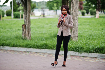 Young african american female doctor hold white coat on hand with a stethoscope posed outdoor.