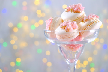 Minimalistic composition with bunch of pink french macaron sweets with crystal shaped marmalade decoration over festive bokeh lights background. Top view, close up, flat lay, copy space.