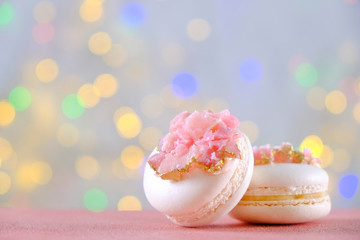 Minimalistic composition with bunch of pink french macaron sweets with crystal shaped marmalade decoration over festive bokeh lights background. Top view, close up, flat lay, copy space.