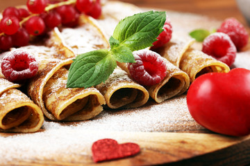 Delicious Tasty Homemade crepes or pancakes with raspberries and mint on rustic background