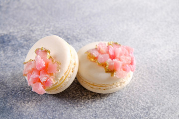 Obraz na płótnie Canvas Minimalistic composition with bunch of white french macaron sweets with pink crystal shaped marmalade decoration over grunged concrete texture background. Top view, close up, flat lay, copy space.