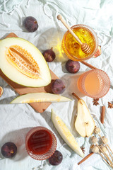 Cut appetizing ripe melon and drinks in stained-glass glasses on a table with a blue tablecloth.