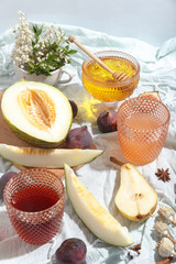 Cut appetizing ripe melon and drinks in stained-glass glasses on a table with a blue tablecloth.