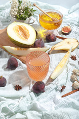 Cut appetizing ripe melon and drinks in stained-glass glasses on a table with a blue tablecloth.