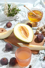 Cut appetizing ripe melon and drinks in stained-glass glasses on a table with a blue tablecloth.