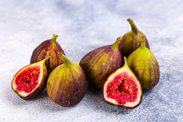 Whole and halved ripe organic delicious figs. Healthy nutritious vegan snack full of fiber and antioxidants, rich on variety of vitamins and minerals. Close up, copy space, top view, background.