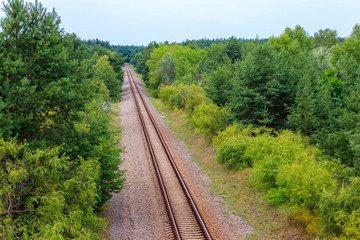 Fototapeta na wymiar Aerial view of railroad track through a green pine forest