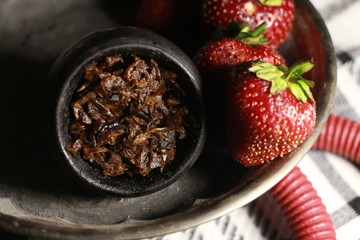 bowl with tobacco for hookah. berries on a black background