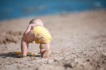 little boy playing with sand by the sea