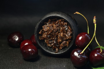bowl with tobacco for hookah. fruits on a black background