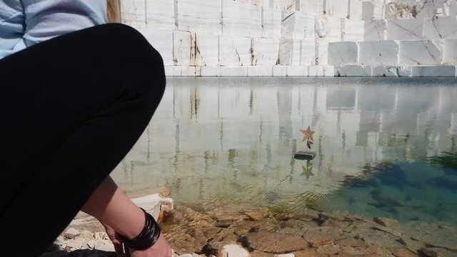 Young woman playing with starr boat toy on marble lake in Pamukkale, it is an abandoned marble mine in Macedonia
