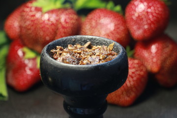 bowl with tobacco for hookah. berries on a black background
